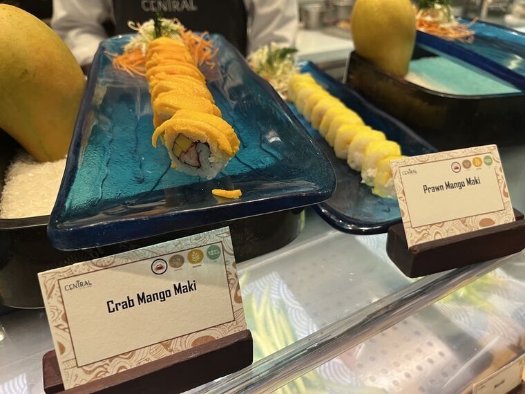 青いガラス皿にマンゴーを巻いた寿司ロールが2種。手前にCrab Mango MakiとPrawn Mango Makiの名札