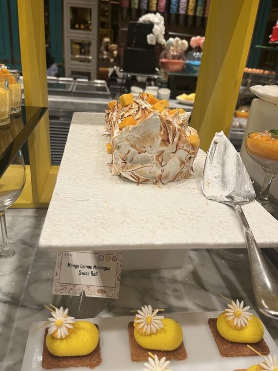 焦げ目のついたメレンゲを乗せたスイスロールのホール。Mango Lemon Meringue Swiss Rollの名札