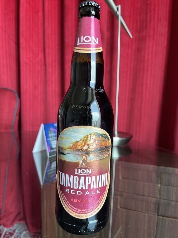 赤いラベルの瓶ビール。LIONのロゴ、崖と海の絵、ライオンのイラスト、LION TAMBAPANNI RED ALE、ABV 7.0%の表記