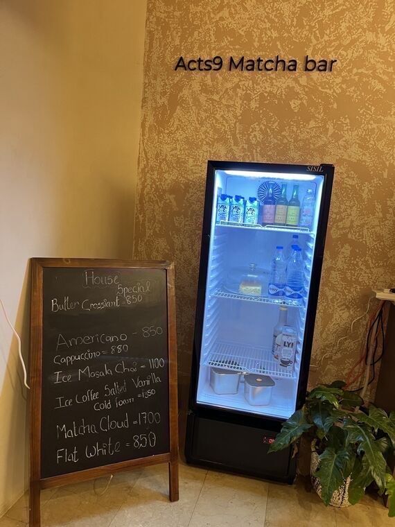店内の壁面にActs9 Matcha barのロゴ。隣に黒板メニューでHouse SpecialとしてButter Croissant 850、Americano 850、Cappuccino 880などが書かれている