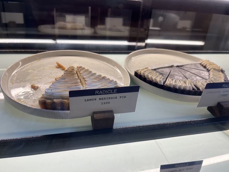 RADICLEのショーケース。レモンメレンゲパイとチョコレートエスプレッソタルトが並び、それぞれRADICLEの値札に1100の表示