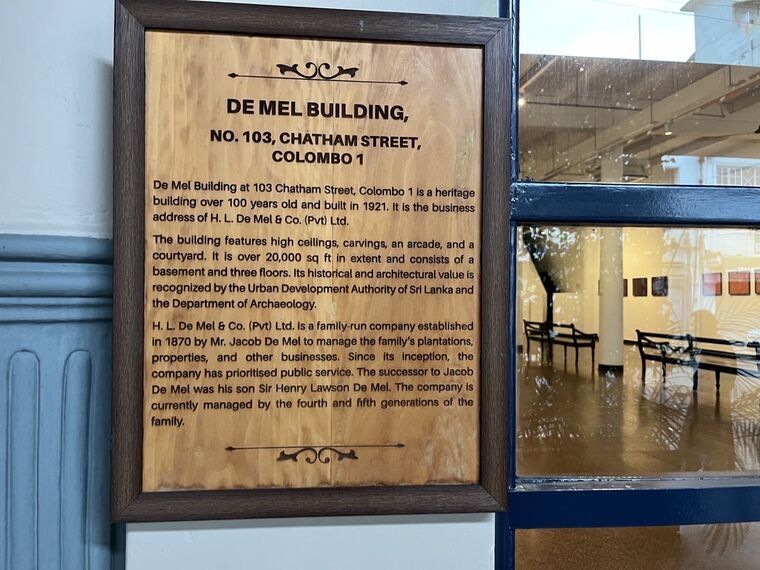 DE MEL BUILDINGの木製プレート。NO. 103, CHATHAM STREET, COLOMBO 1、1921年築、20,000平方フィート、地下と3フロアからなる建物であることなどが英語で書かれている
