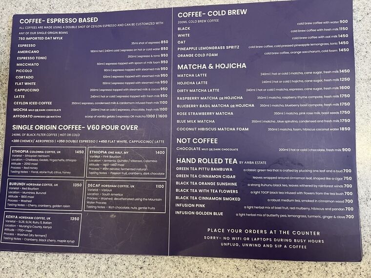 RADICLEの紺色のドリンクメニュー。COFFEE-ESPRESSO BASED、SINGLE ORIGIN COFFEE V60 POUR OVER、COFFEE-COLD BREW、MATCHA &amp; HOJICHA、HAND ROLLED TEAの各セクションと価格が並ぶ