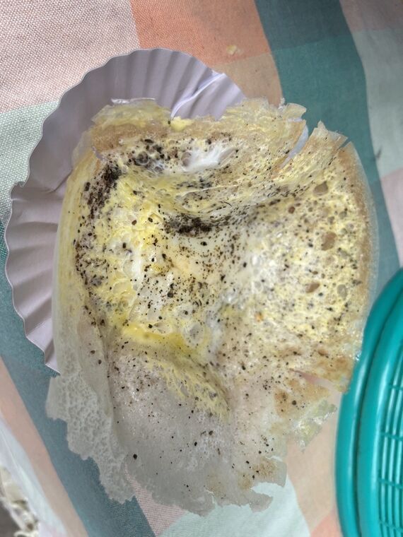 紙のケースに乗ったビッタラアーッパ。薄く広がった生地の中央に卵が落とされ、黒胡椒が振られている。縁は薄くパリパリした状態