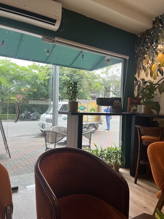 The Mango Cafe by Nelnaの窓際の席から見た通り。Nelnaのロゴが入った白い軽トラックが店の前に停まっている。手前のカウンター席とエアコン、右手の壁にマンゴーの壁紙