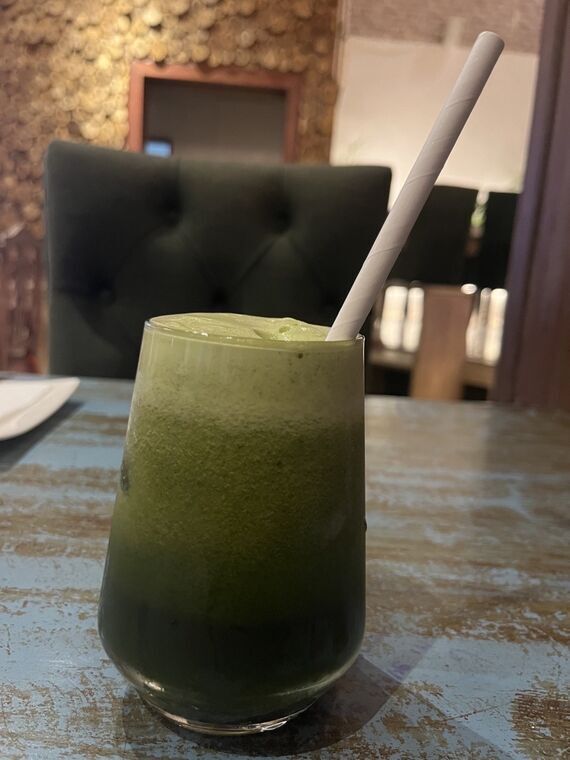 The BarnesburyのCucumber mint cooler。背の高いグラスに濃い緑色の飲み物が注がれ、紙ストローが差してある。上部は明るい緑、下部は濃い緑のグラデーション