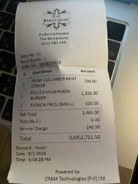 The Barnesburyのレシート。FRESH CUCUMBER MINT COOLER 790.00、PULLED MUSHROOM BURGER 1,350.00、FRENCH FRIES SMALL 325.00、Sub Total 2,465.00、Service Charge 246.50、Total LKR 2,711.50の記載