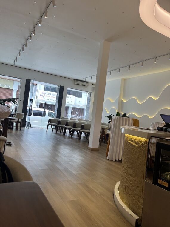 Kafenio Colomboの店内。白い壁に波形の間接照明、木の床、金色の装飾が入ったカウンター。奥に椅子が横一列に並べられている
