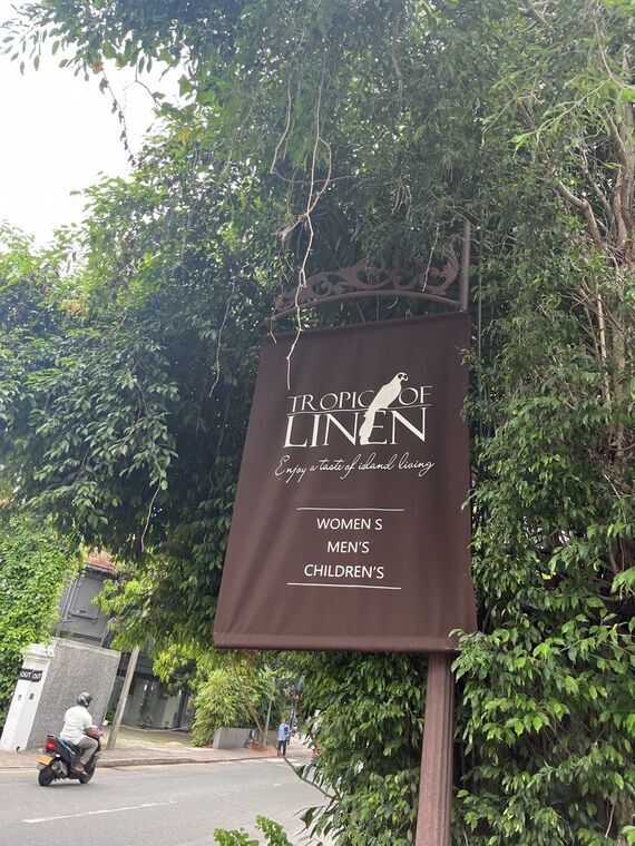 通り沿いに立てられたTropic of Linenの看板。Enjoy a taste of island livingの一文とWOMEN'S MEN'S CHILDREN'Sの表示、鳥のロゴ