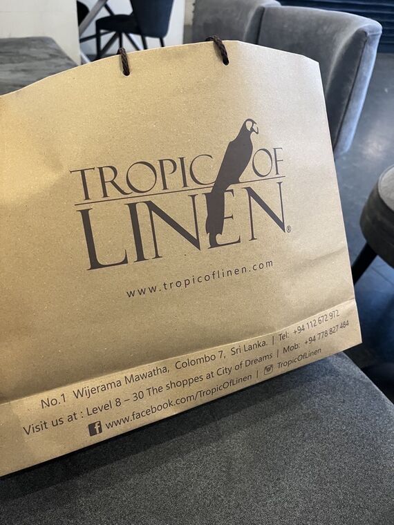 Tropic of Linenの紙袋。鳥のロゴと店名、公式サイトのアドレス、コロンボ7の住所とCity of Dreamsの店舗表記が印字されている