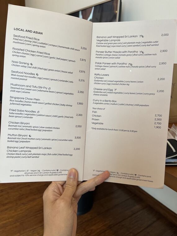 IN-ROOM DINING MENUのLOCAL AND ASIANのページ。Mutton Biriyani 3,500、Chicken Biryani 2,550などの価格。下部に10%のサービス料と税が加算される旨の注記