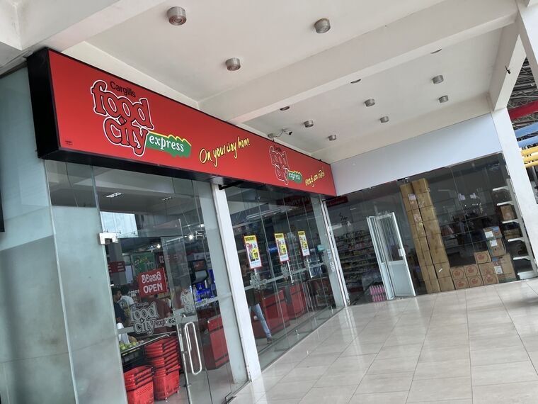 赤い看板のCargills Food City express。On your way homeの文字、ガラス扉の奥に商品棚と赤い買い物カゴ