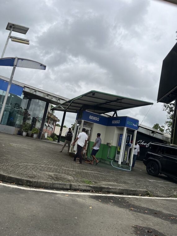 GENSOとECO Parkの看板が付いた屋根付きの充電スタンド。chargeNETの充電器に人が集まっている。右に黒いSUV