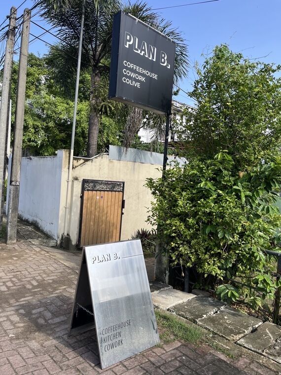 PLAN B.と書かれた黒い看板。COFFEEHOUSE COWORK COLIVEの文字。手前に銀色のA型看板でCOFFEEHOUSE KITCHEN COWORKと表示