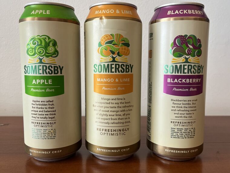 SOMERSBYの500ml缶3本を横並びにしたところ。左からApple、マンゴーライム、Blackberry。AppleとBlackberryにはREFRESHINGLY OPTIMISTICの下に栄養成分の印字があるが、中央のマンゴーライムは同じ位置が空白