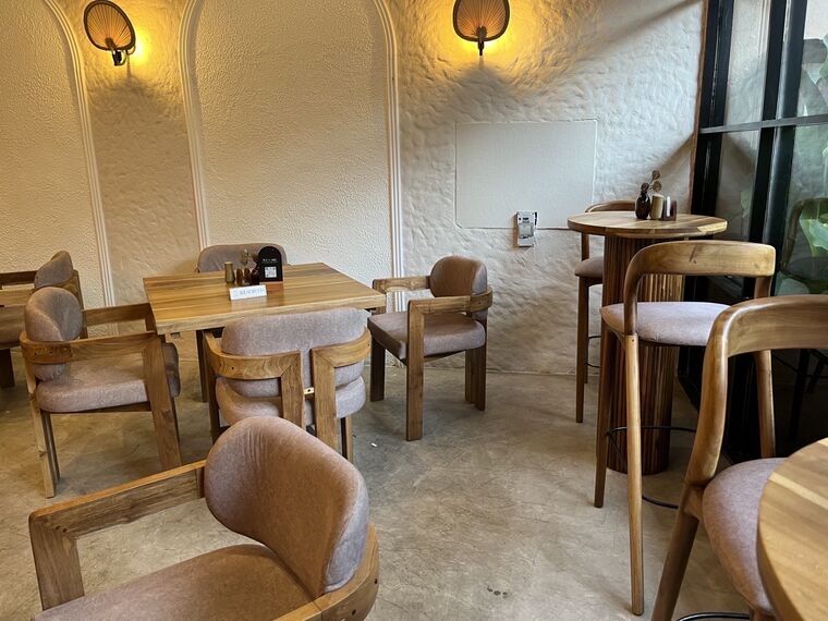 Latte CeylonのRESERVED札が置かれたテーブル席。アーチ装飾の白壁とうちわ形のランプ