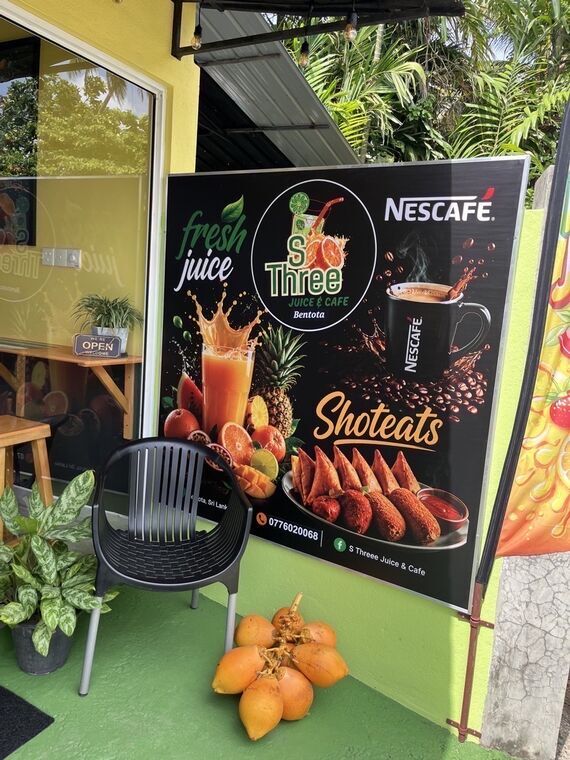 S Three JUICE &amp; CAFE Bentotaの店頭看板。フレッシュジュースとShoteatsの写真、OPENの札