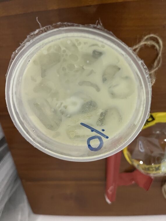 カップを真上から撮影。薄い黄緑色の抹茶ラテと氷、蓋に青いペンで書かれた0のマーキング