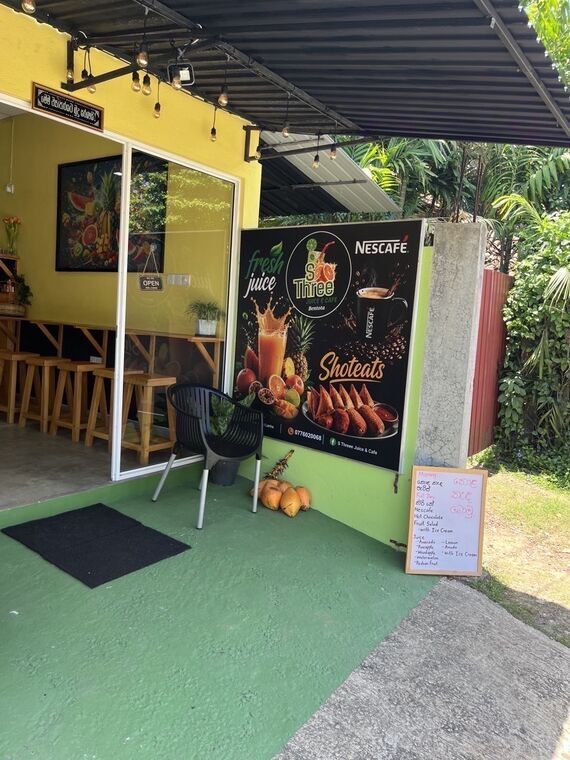 S Threeの店頭。緑の床と黄色い壁、Nescafeの大看板と、外に置かれたA型の手書きボード