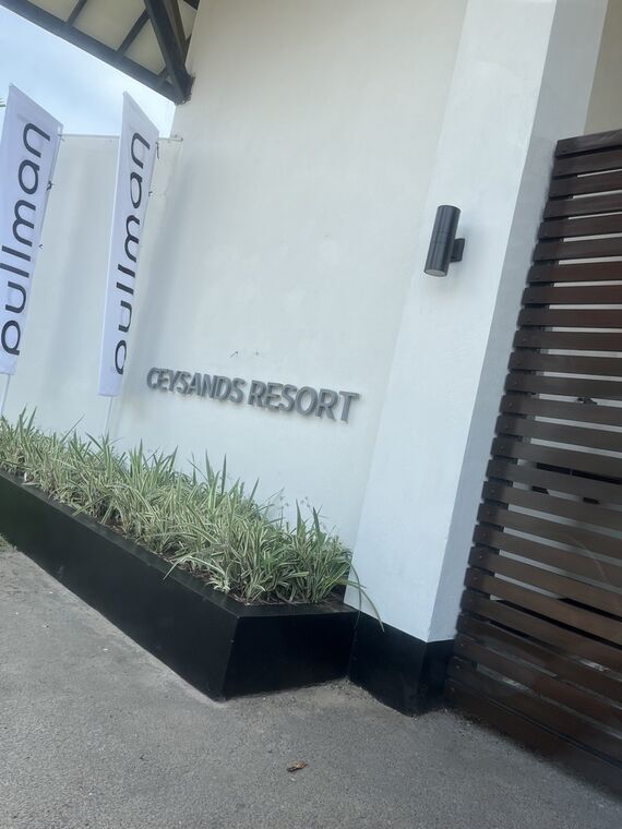 リゾート入口の看板。CEYSANDS RESORTの立体文字の隣にPullmanのバナー旗が2枚立っている