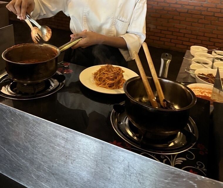 パスタステーションで鍋からスパゲティを取り分けているところ。手前の皿に盛られたパスタ