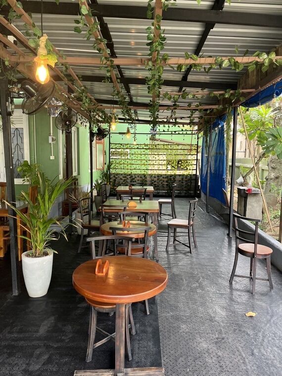 Jaffna Virunthuの客席の通路。つる植物が這う天井、扇風機、丸テーブルと椅子が奥まで並ぶ
