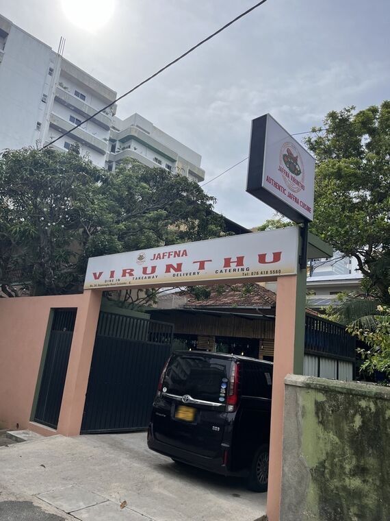 Jaffna Virunthuの縦看板。AUTHENTIC JAFFNA CUISINEの表記と、奥の高層マンション