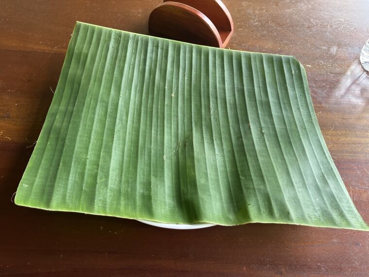 テーブルの皿の上に敷かれた大きなバナナの葉