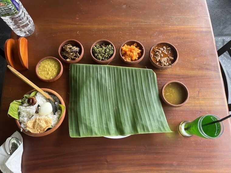 Jaffna Virunthuのポットライス一式を真上から。素焼きのライス器、バナナの葉の皿、カレーの小鉢5つ、緑色のジュース