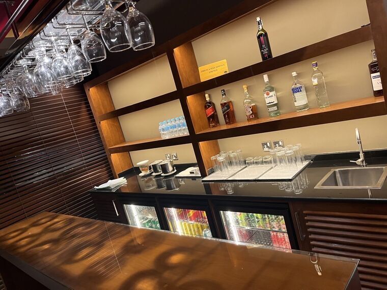 Lotus Loungeのセルフサービスバー。洋酒のボトルと冷蔵ケースの缶飲料