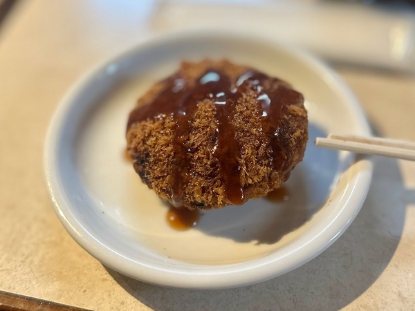 特製メンチにソースをかける