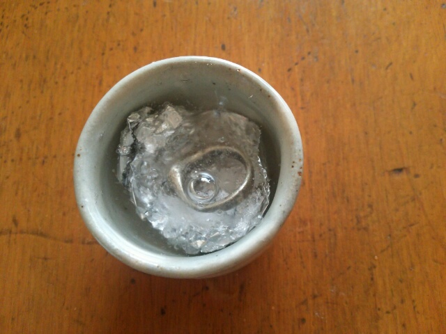 お猪口の中に重曹とアルミホイルを入れ黒ずんだシルバーリングを浸した画像