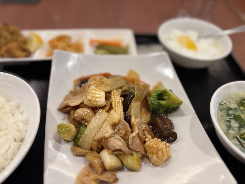 梅蘭 上野の森さくらテラス店のランチセット。野菜と海鮮の炒め物、ご飯、スープ、小鉢が並ぶ。