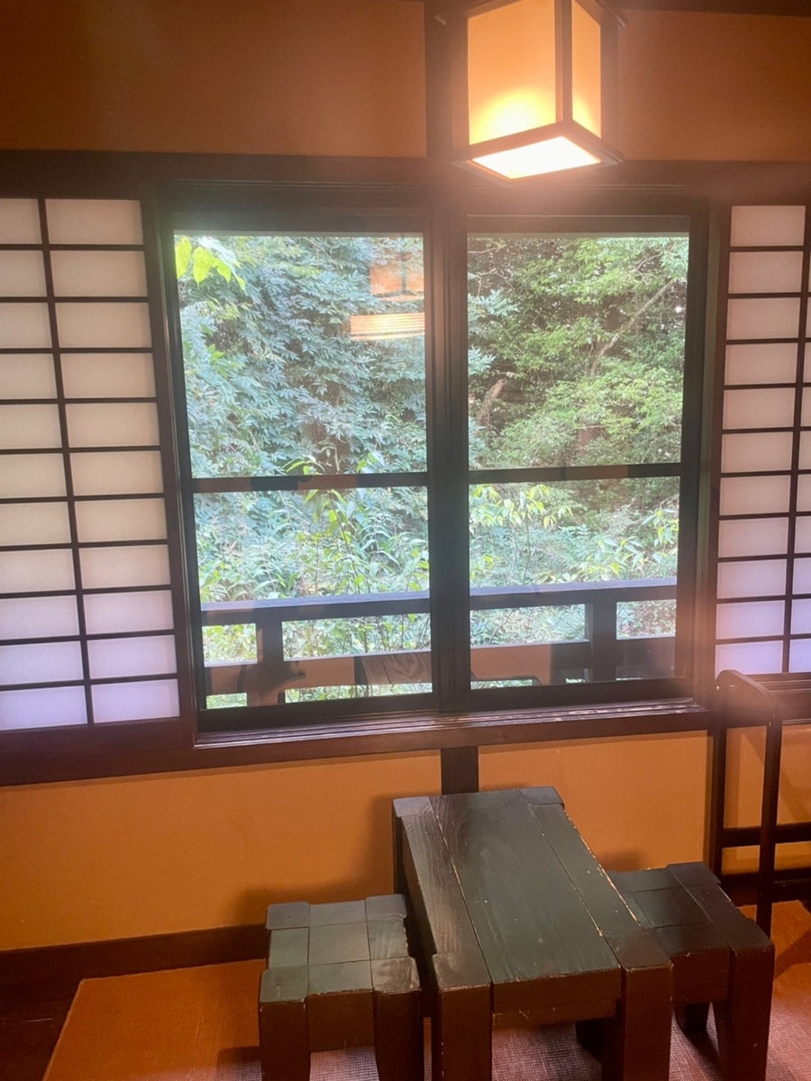 部屋の広縁にあるテーブルとイスそして窓から緑が見える