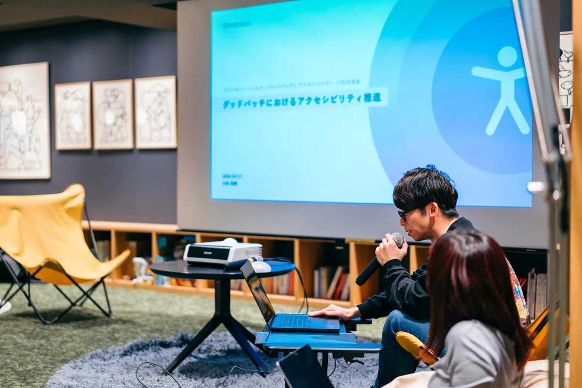 LTで発表している様子：男性がマイクを持って話している。スライドには「グッドパッチにおけるアクセシビリティ推進」と書かれている