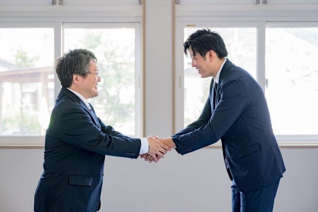 両手で握手をするビジネスマン