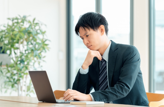 ノートPCを見て困った表情の男性
