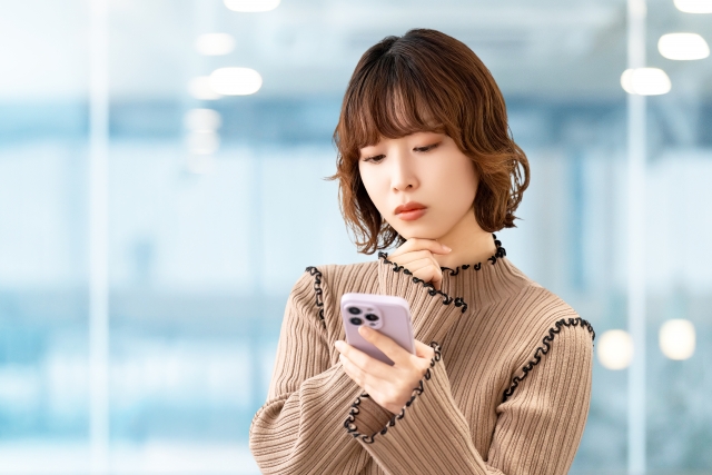 スマホを見て困った表情の女性