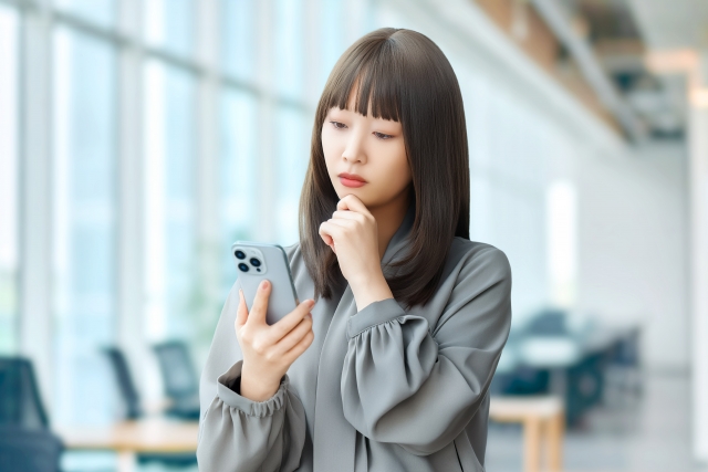 スマホを見て困った表情の女性