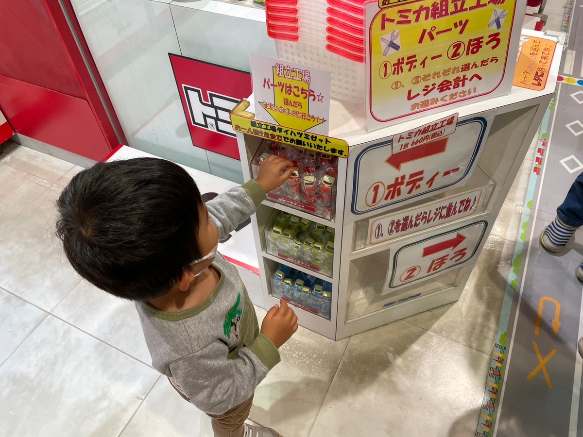 東京駅の東京一番街・東京キャラクターストリート「トミカショップ」にあるトミカ組み立て工場でパーツを選ぶ男児