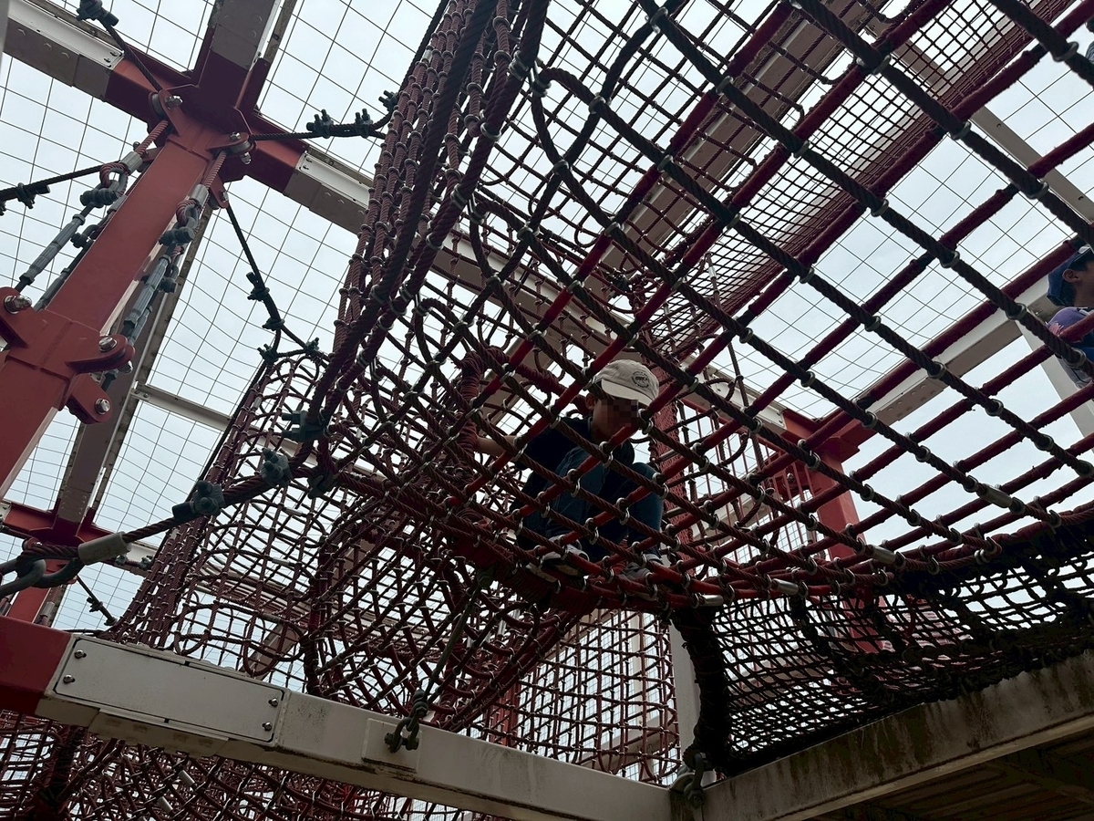 豊中市観光スポット｜飛行機の離発着を見ながら遊具で遊べる公園「伊丹スカイパーク」の遊具エリアにある巨大立体迷路で遊ぶ男児