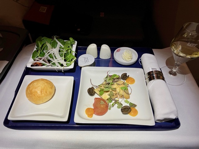 ビジネススクラスの機内食(前菜)。彩り豊かなサラダ、パン、オードブルのトレイ