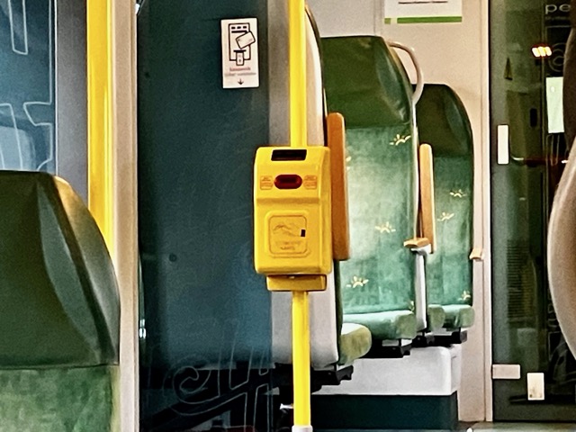 列車の車内に設置された黄色い自動刻印機（バリデーター）。乗車券を有効化する装置