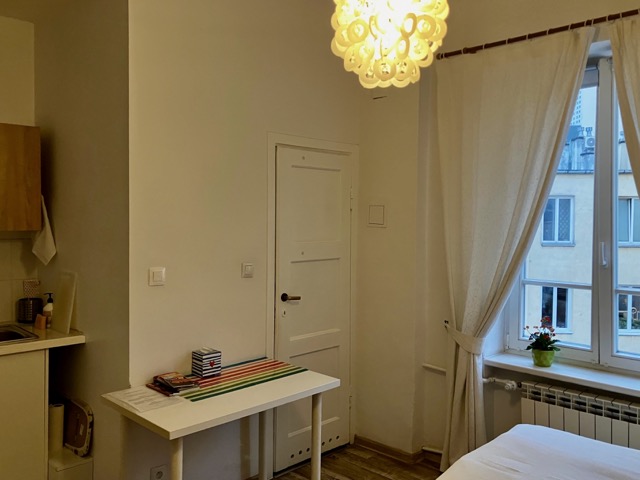 入口から窓際方向を見た部屋のレイアウト。バスルームへのドアと、デスクやヒーターが設置された居住スペース
