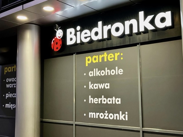 民泊の近くにあるポーランドの人気スーパー「Biedronka（ビエドロンカ）」の外観。てんとう虫のロゴと、フロアごとの取扱商品（アルコール、コーヒーなど）を示す看板