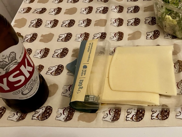 宿のテーブルに並べられたポーランドのビール「Tyskie（ティスキェ）」のボトルと、スーパーで購入したスライスチーズ
