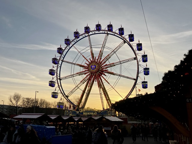 夕焼け空にシルエットが浮かび上がるクリスマスマーケットの巨大な観覧車