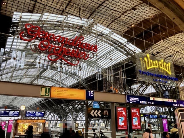 ライプツィヒ中央駅のガラス天井を背景に、ゲヴァントハウス管弦楽団と聖トーマス教会合唱団の大きなネオン看板