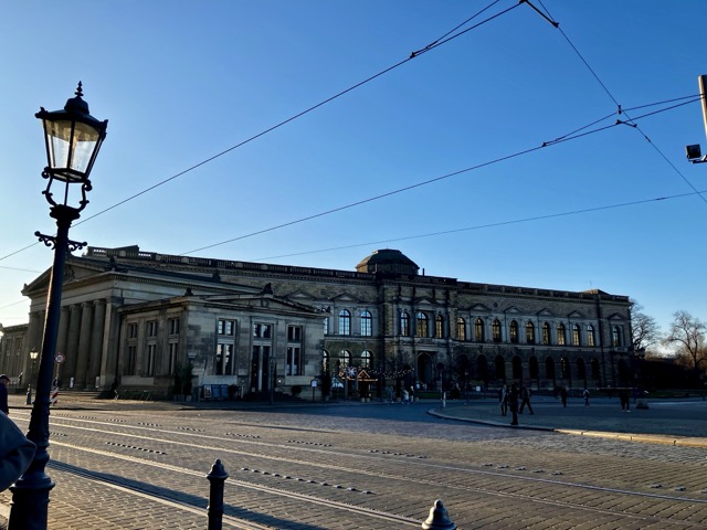 ドレスデン旧市街のツヴィンガー宮殿周辺の歴史的な街並み。路面電車の線路とガス灯風の街灯が情緒的
