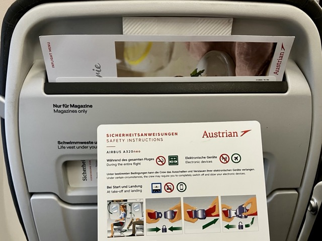 オーストリア航空A320neoの機内シートバックポケットに収納された、安全のしおり（Sicherheitsanweisungen）とインフライトメニュー（Inflight Menu）